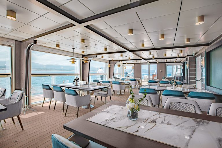 The specialty restaurant on Ocean Victory with various tables ang huge ocean view windows.