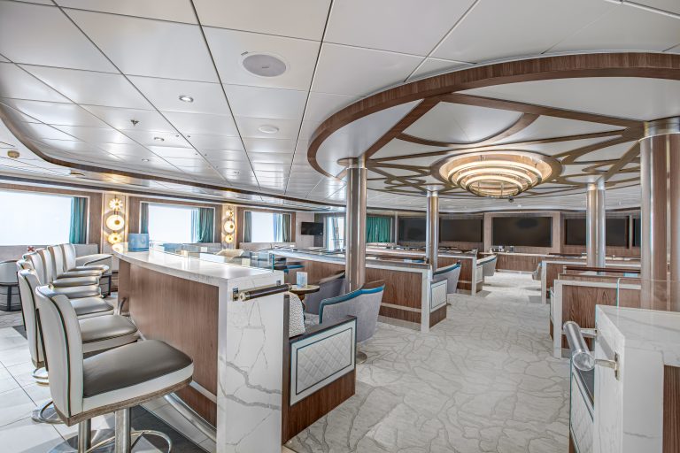 The lecture room on Ocean Victory showing multiple rows of seating, large flat screen TV's and windows.